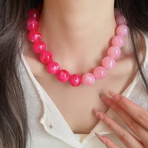 Close-up of a vibrant pink gradient dopamine acrylic beaded necklace on a female model.