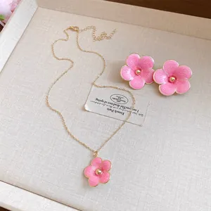 Vista detallada de un elegante conjunto de joyas con flores de esmalte rosado