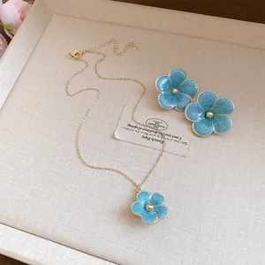 Detalle del hermoso conjunto de collar y pendientes de flores de esmalte azul claro.