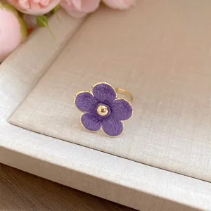Detalle de un anillo ajustable de flor en esmalte púrpura con elegantes tonos dorados.