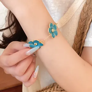 Primer plano de una pulsera de cadena dorada con flores de esmalte azul vibrante
