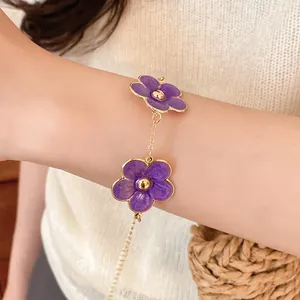 Primer plano de una elegante pulsera de flores de esmalte morado con cadena dorada