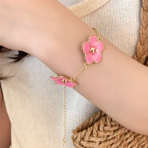 Primer plano de una elegante pulsera con flores de esmalte rosa en la muñeca de mujer