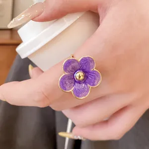 Elegante anillo de flor de esmalte morado usado en la mano, primer plano detallado