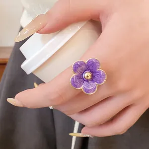 Primer plano de un elegante anillo de flor en esmalte púrpura con borde dorado
