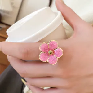 Primer plano detallado de un anillo de flor de esmalte rosa al sostener una taza