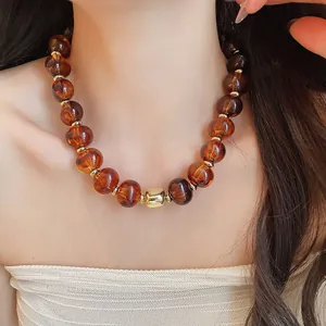 Nahaufnahme der bernsteinfarbenen Perlen und des goldenen Elements am Sommercollier.