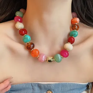 Lebhafte bunte Perlenkette mit goldfarbenen Akzenten am Schlüsselbein des Models.