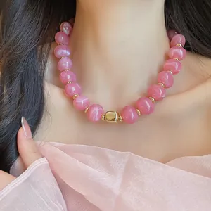 Nahaufnahme einer rosa marmorierten Perlenkette mit goldenem Akzent an einem Modell