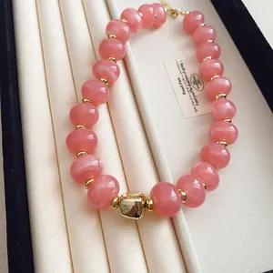Makroansicht einer stilvollen rosa Katzenaugen-Perlenkette mit goldenem Quadratanhänger