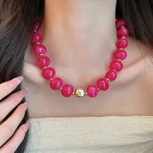 Detailaufnahme einer leuchtend magentafarbenen Perlenkette mit glänzenden Goldakzenten.
