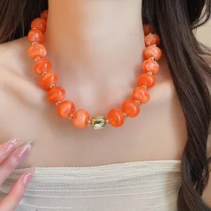Detailansicht der sommerlichen bunten Perlenkette mit orangefarbenem Marmormuster an einem Modell