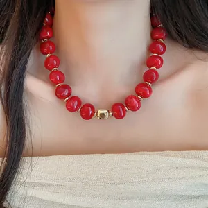 Detailansicht einer leuchtend roten Perlenkette mit goldenen Akzenten am asiatischen Model