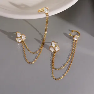 Detailed view of gold chain tassel earrings with pear-shaped cubic zirconia stones.