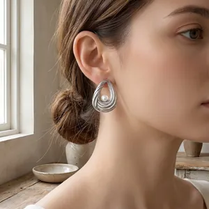 Nahaufnahme eines silbernen Wassertropfen-Ohrrings mit Perle an einem weiblichen Model