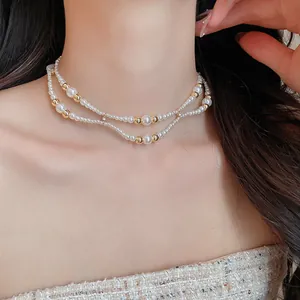 Elegante close-up van een dubbellaagse parel- en gouden kralenketting op een model