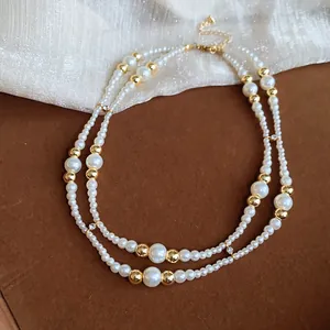 Detail van een retro dubbellaagse parelketting met gouden kralen en sprankelende strassteentjes.
