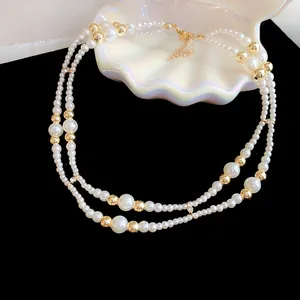 Elegante dubbellaagse parelketting met gouden kralen op zwarte achtergrond met schelp
