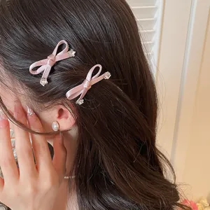 Detailweergave van twee zoete roze strik haarclips gedragen op lang bruin haar