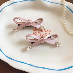 Detail van zoete roze satijnen strik haarspelden met stervormige kristalaccenten