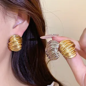Close-up of vintage ribbed texture geometric stud earrings in gold and silver finish