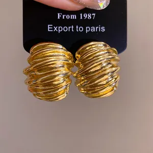 Detailed macro view of vintage gold stud earrings featuring textured geometric wave patterns