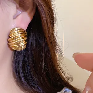 Detailed close-up showing the vintage gold geometric textured stud earrings on an ear