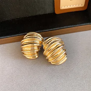 Close-up detail view of vintage gold stud earrings with textured geometric spiral design