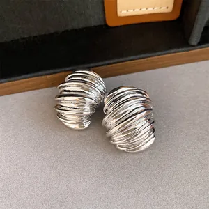 Close-up of retro silver stud earrings featuring a geometric textured spiral design.