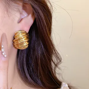 Detailed close-up of vintage gold stud earrings with geometric texture and silver needle.
