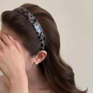 Detail shot of a leopard print headband with small colored rhinestones on a model