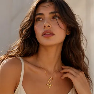 Gros plan d'un collier pendentif colibri doré avec fermoir mousqueton porté par un mannequin.
