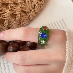Detailansicht eines grünen Harzrings mit bunten eingebetteten Kristall-Strasssteinen.