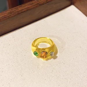Nahaufnahme eines gelben Harzrings mit bunten eingelegten Strasssteinen in einer Schale.