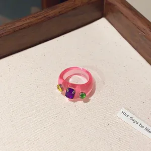 Nahaufnahme eines trendigen rosa Harzrings mit bunten Strasssteinen auf weißem Grund