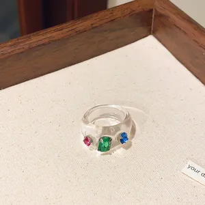 Nahaufnahme eines massiven transparenten Harzrings mit leuchtenden bunten Strasssteinen
