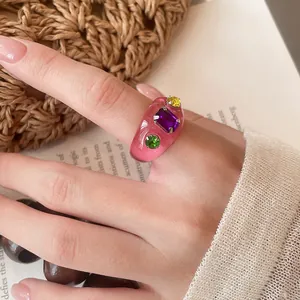 Detailansicht eines trendigen rosa Harzrings mit bunten Kristallen an der Hand eines Models