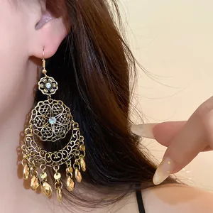 Primo piano di orecchini pendenti boho retrò con fiori di strass e nappe dorate