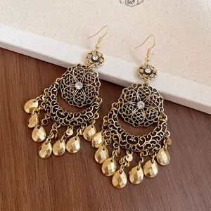 Dettaglio di orecchini vintage bohémien dorati con nappe in metallo e strass brillanti.