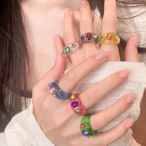 Bunte Harzringe mit funkelnden eingebetteten Strasssteinen an den Fingern für einen trendigen Look.