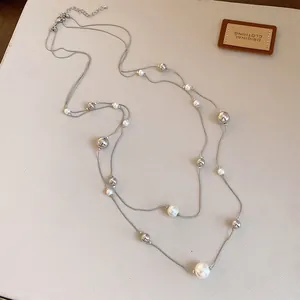 Detalle de un collar francés de dos capas con perlas blancas y cuentas plateadas brillantes.
