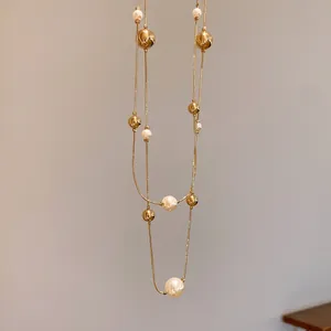 Detalle de un elegante collar dorado de dos capas con perlas blancas brillantes y cuentas