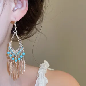 Detailweergave van elegante bohemien oorbellen met verenkwastjes en turquoise kralen