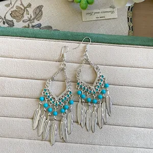 Detailweergave van bohemian oorbellen met turquoise kralen en zilveren vederkwastjes