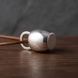 Détail macro d'un pendentif bouilloire en argent poli minimaliste avec cordon brun