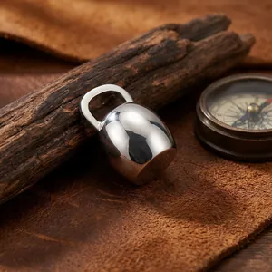 Gros plan d'un pendentif bouilloire en argent poli minimaliste sur fond de cuir rustique.