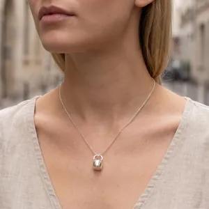 Gros plan d'un collier pendentif bouilloire en argent minimaliste sur un mannequin