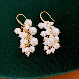 Elegante oorbellen met pareltrossen in paleisstijl met gouden haken op groen fluweel.