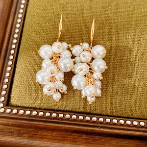 Detailweergave van elegante gouden oorbellen met witte parels op groene achtergrond