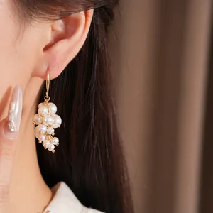 Elegante goudkleurige oorhangers met een delicaat clusterdetail van witte parels.